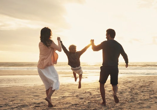 Parents holding their son at the beach.