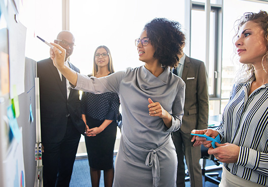 woman standing in board meeting presenting
