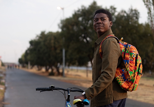 A man gazes into the distance while holding onto his bicycle.